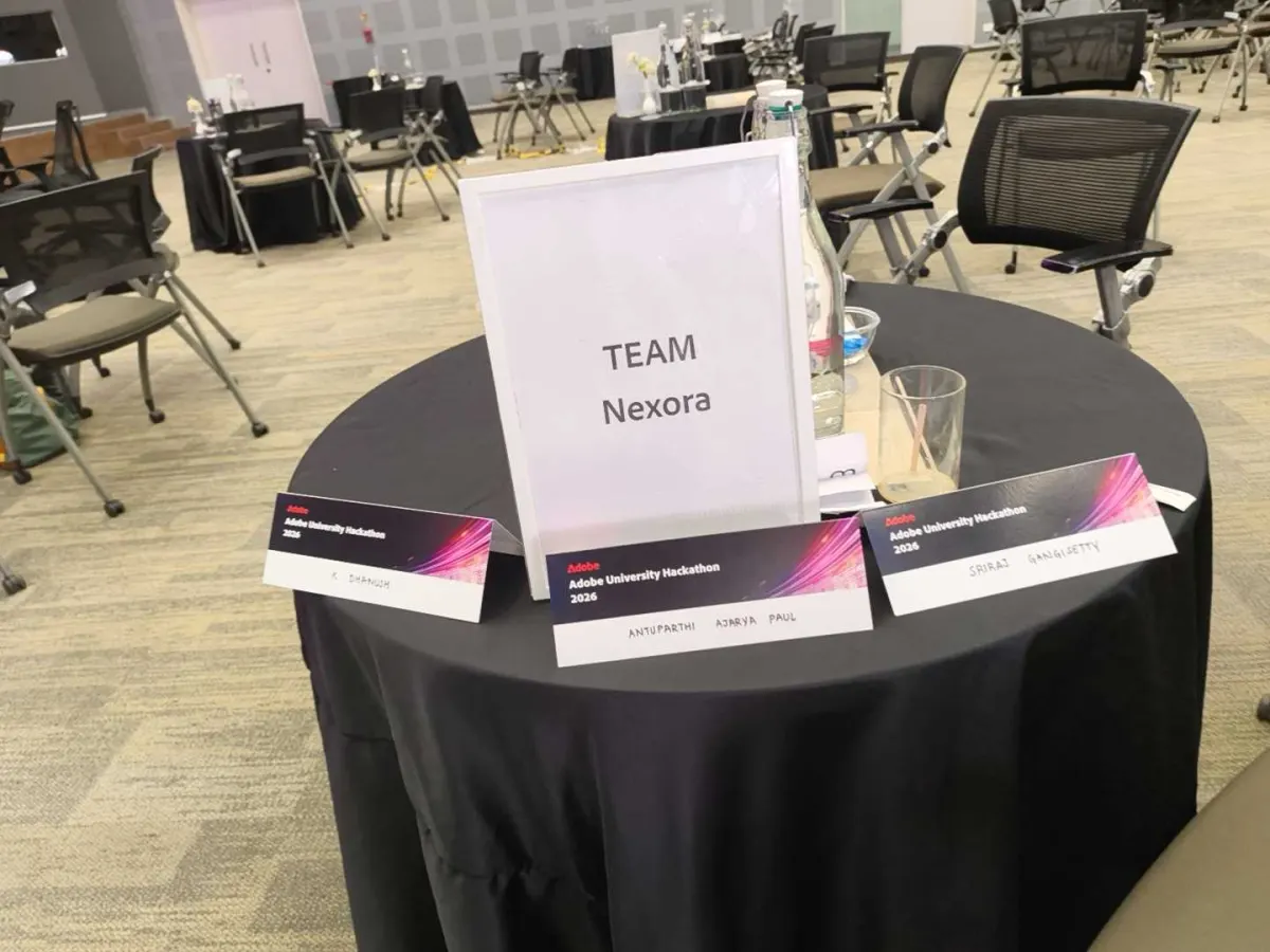 The Team Nexora table at the Adobe University Hackathon 2026 Grand Finale, with a framed team sign and three Adobe name cards