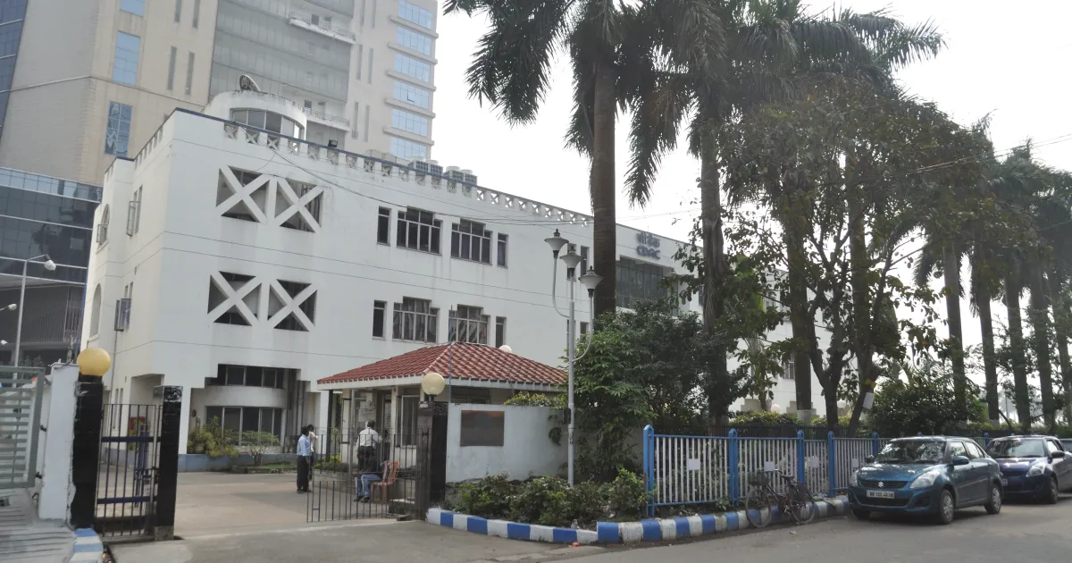 The white C-DAC office building in Sector V, Salt Lake City, Kolkata, with palm trees and a gate in front
