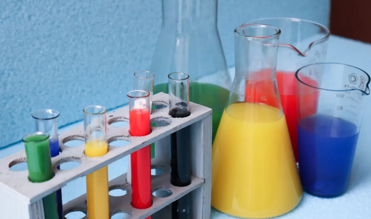 Laboratory glassware, test tubes in a rack and flasks with coloured liquids on a lab table