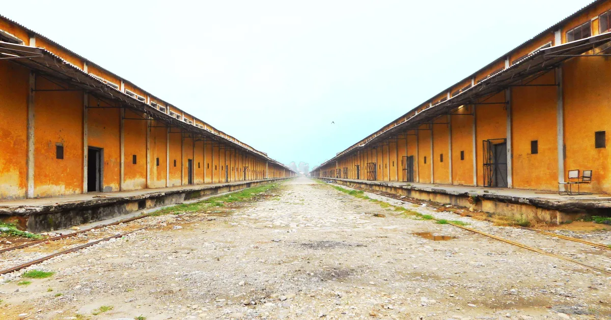 Two long rows of orange warehouse sheds with loading platforms at the CWC Base Depot in Bamanheri, Muzaffarnagar