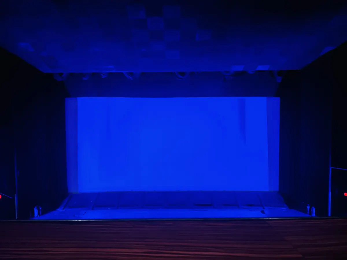 A cinema screen lit in deep blue light, with dark curtains on both sides