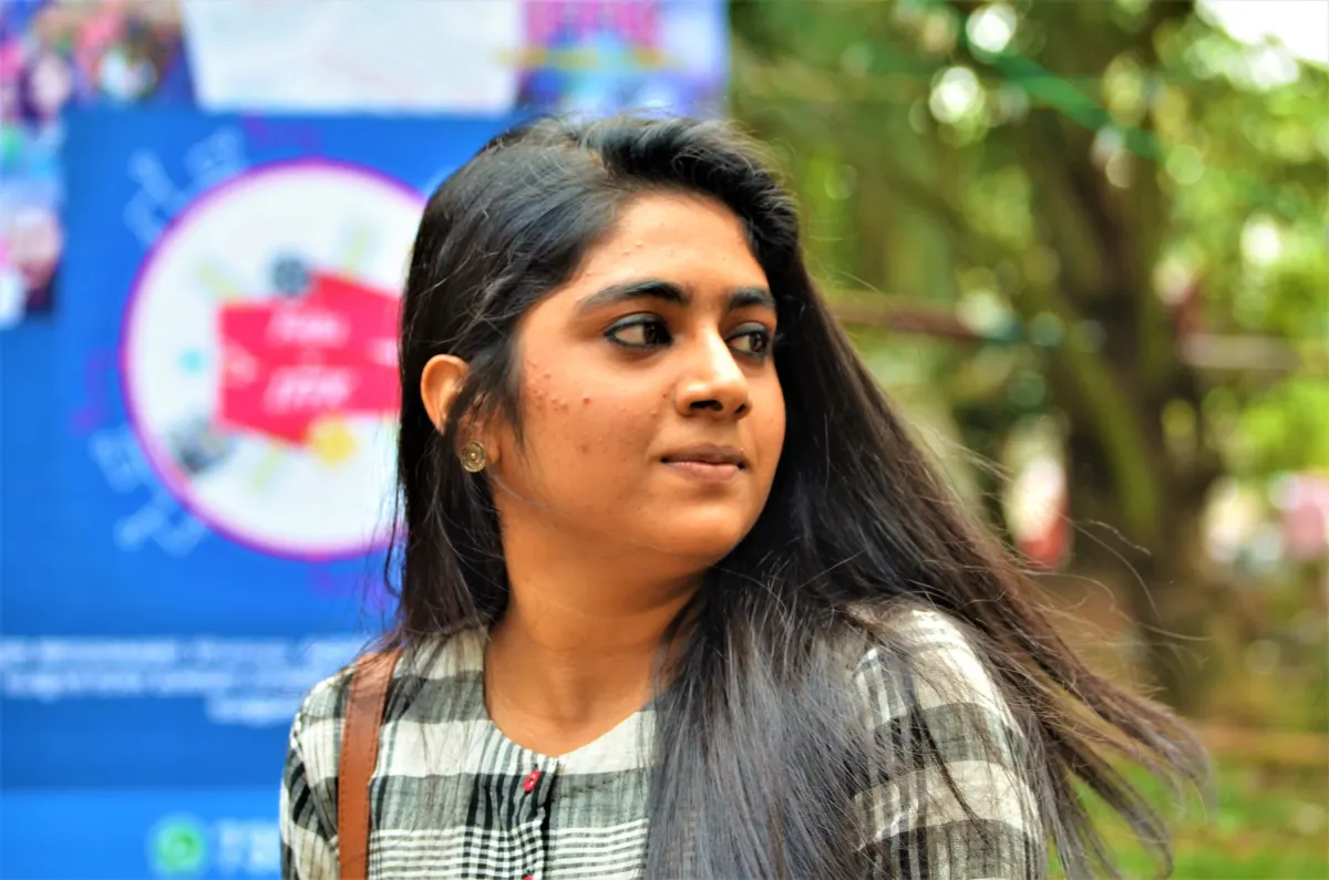 Actor Nimisha Sajayan with long hair in a checked shirt, looking to the side at an outdoor event