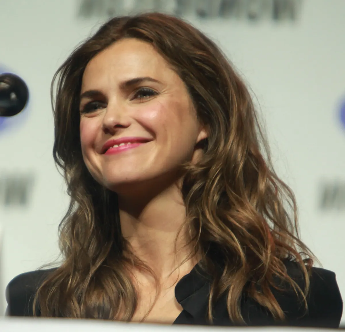 Actor Keri Russell with long wavy hair smiling on a panel stage