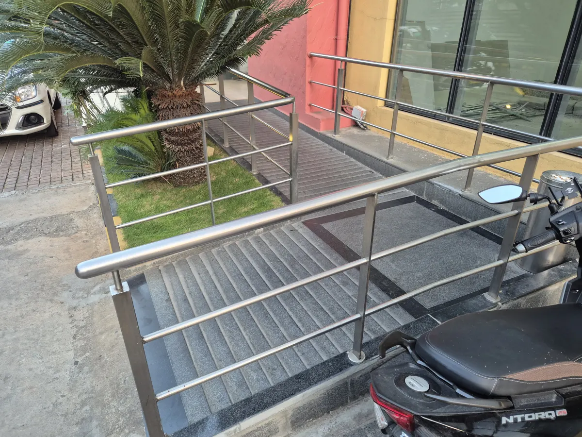 A tiled wheelchair ramp with steel handrails leading up to a building entrance