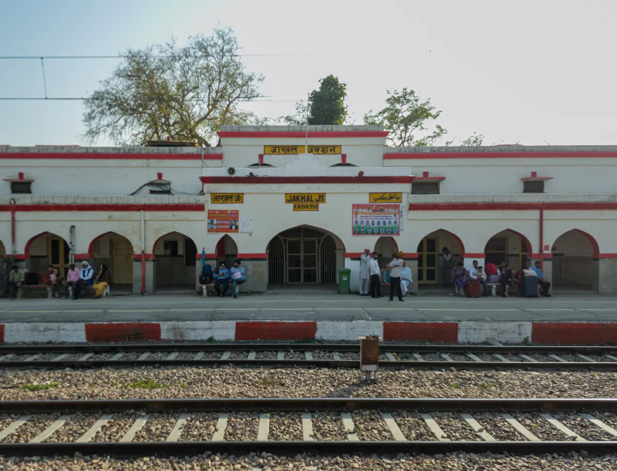 Main building of Jakhal Junction railway station with passengers sitting on the platform