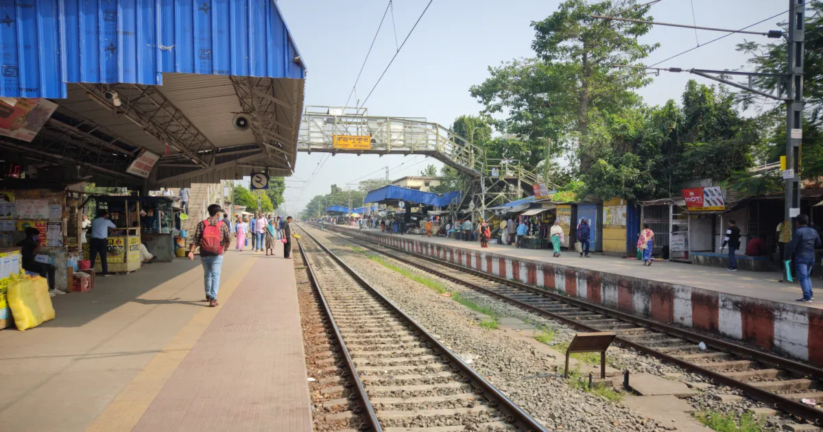 Platform and tracks at Dattapukur railway station in West Bengal, with passengers walking under the station shed