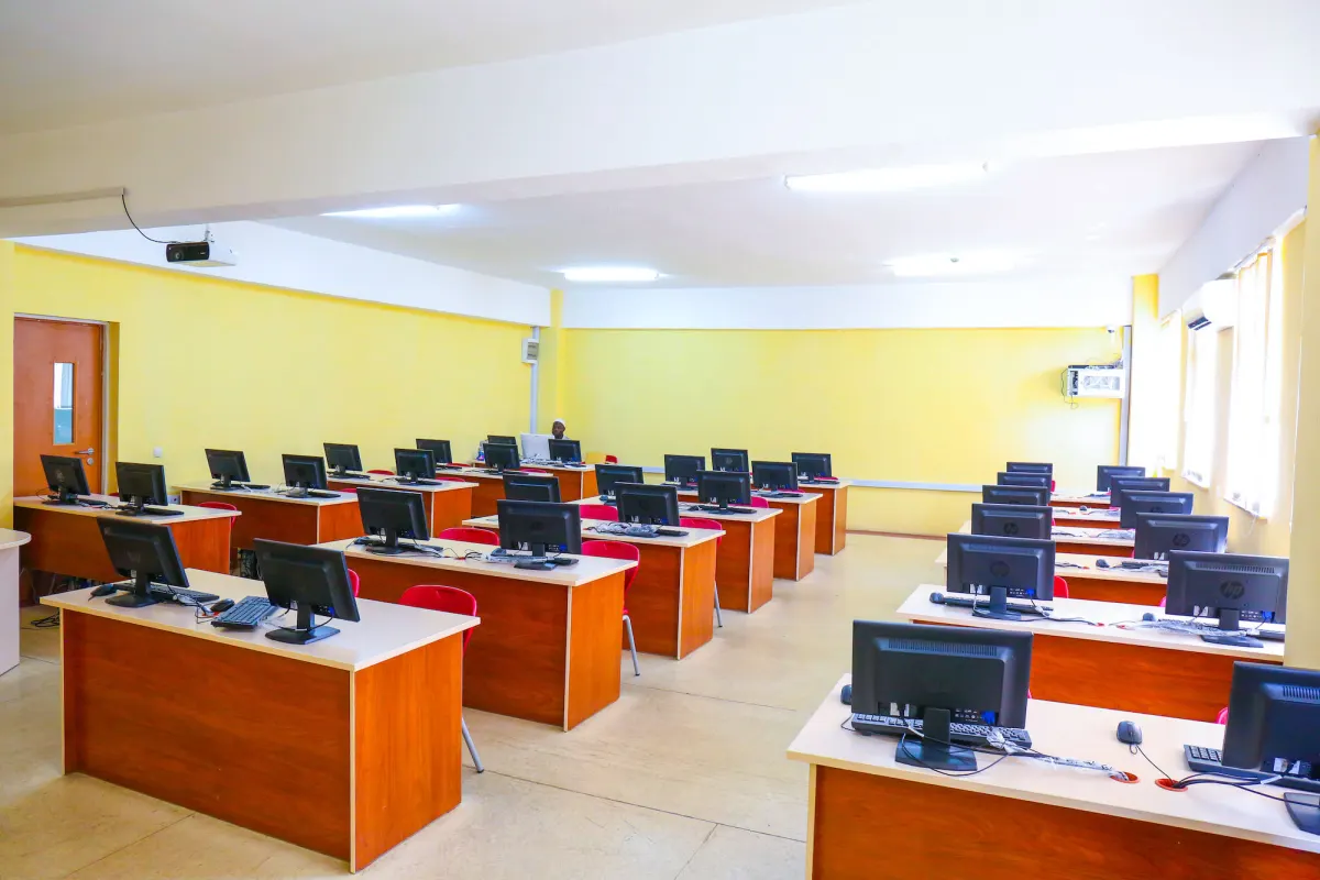 Rows of desktop computers on wooden desks in an empty computer lab, similar to an online exam centre