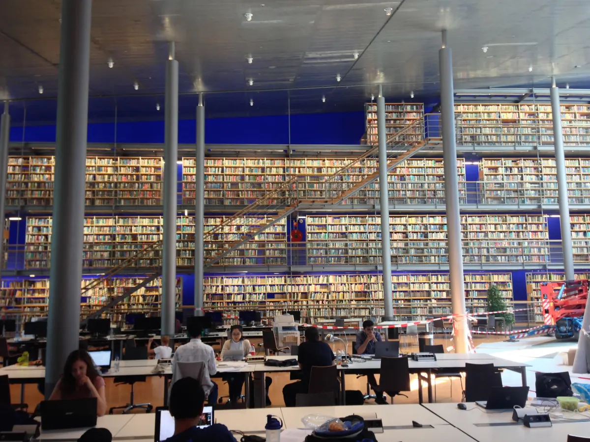 Students studying at long desks in a large library