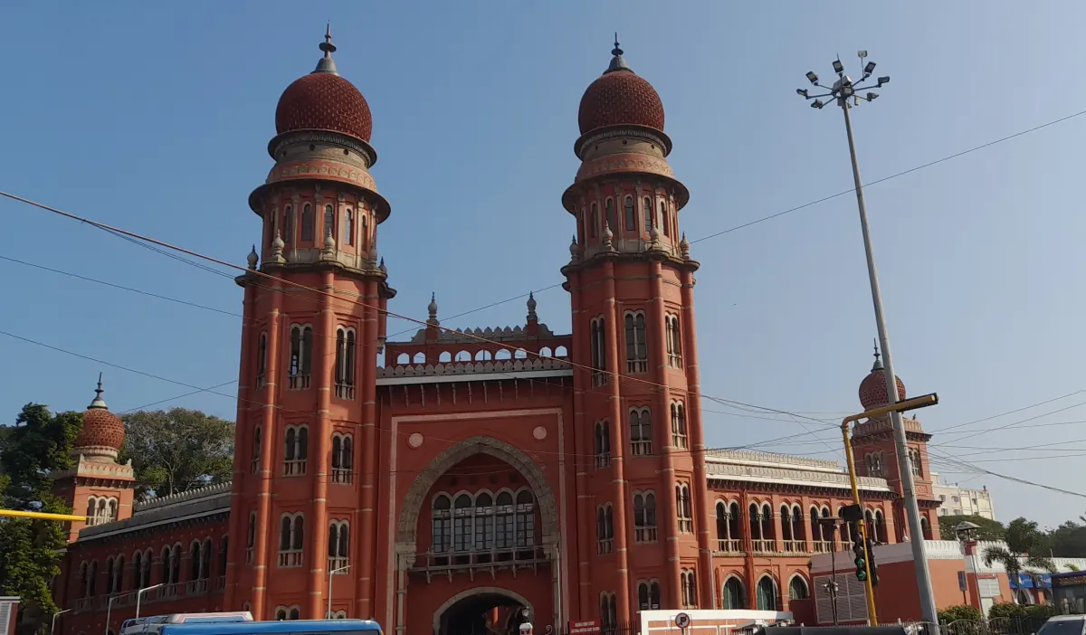 The red Indo-Saracenic building of the Madras High Court in Chennai, with its two domed towers against a blue sky