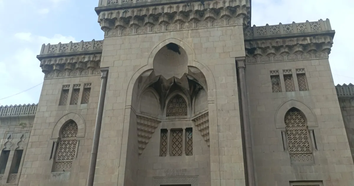 The grey stone front of the Arts College building at Osmania University, Hyderabad, with its tall arched entrance