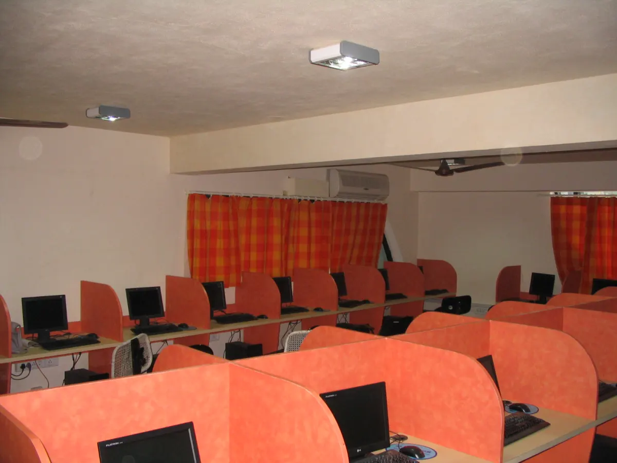 Rows of desktop computers in orange cubicles inside an empty computer lab