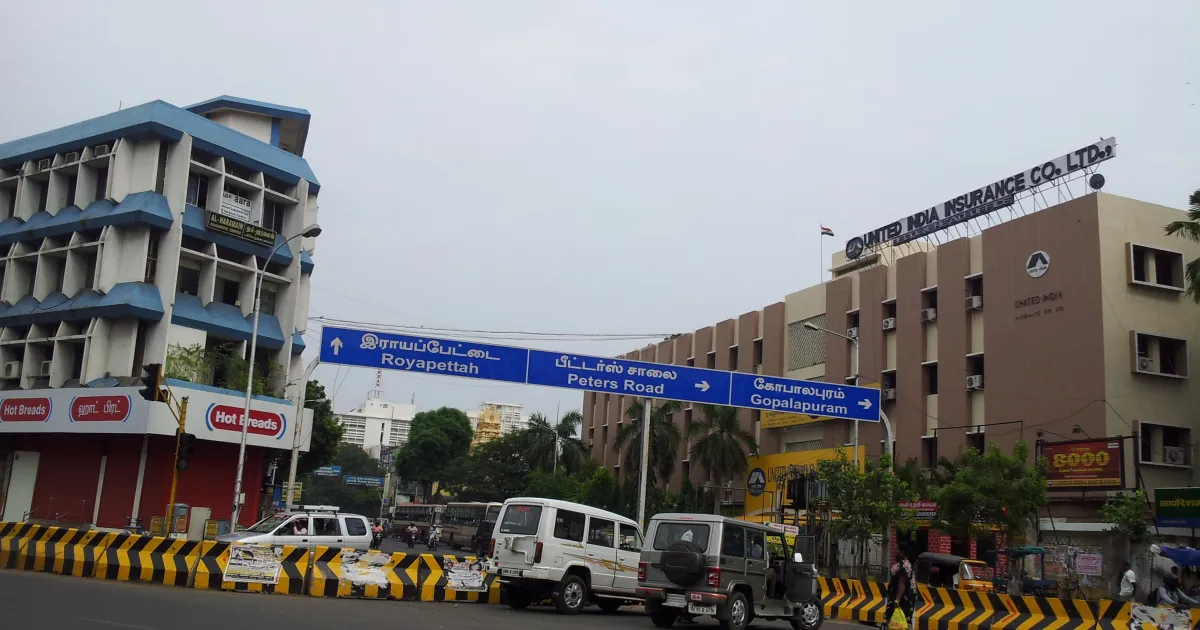 The United India Insurance head office building in Chennai, seen from a busy road with blue direction signboards