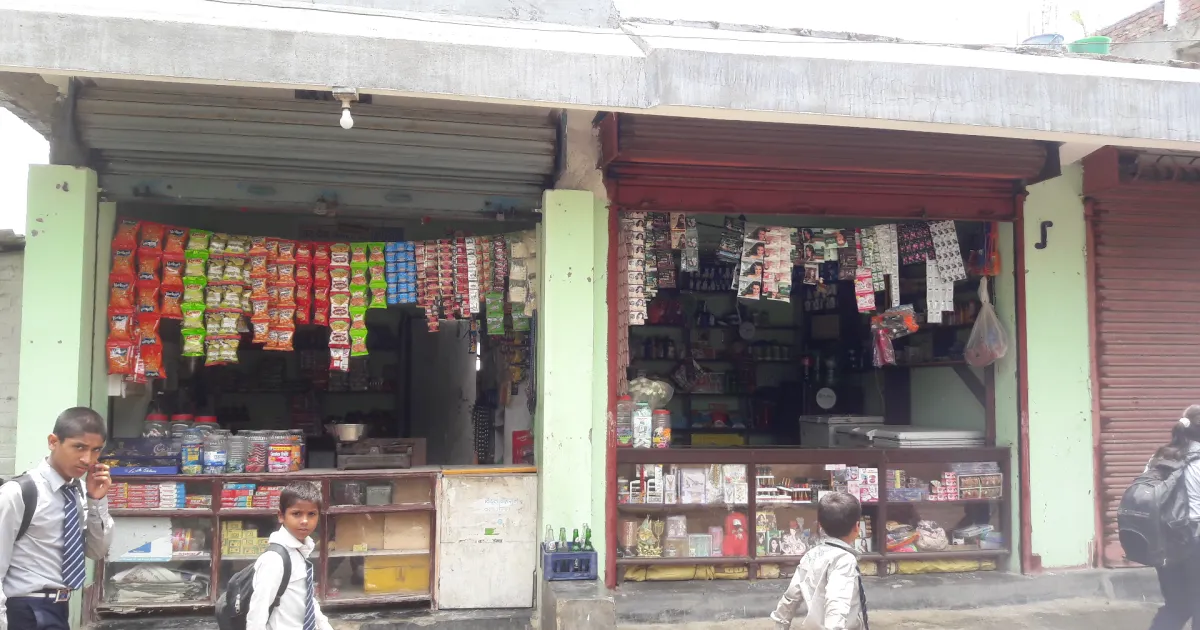 A small kirana store front with snack packets hanging at the counter