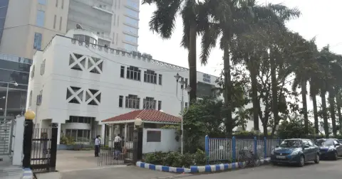 The white C-DAC office building in Sector V, Salt Lake City, Kolkata, with palm trees and a gate in front