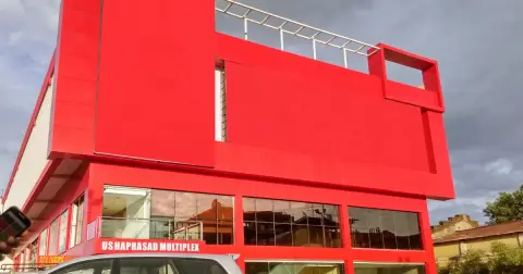 Red front of the Usha Prasad multiplex in Nizamabad, Telangana, with its box office sign at the bottom left