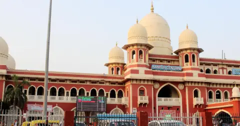 Red and cream building of Kanpur Central railway station with domes and arches, seen from the road