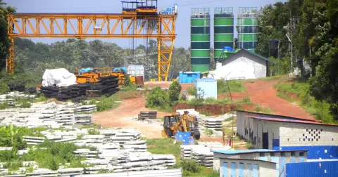 A gantry crane and stacks of precast concrete girders in a casting yard for the Kollam Bypass road project in Kerala