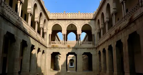 The stone inner courtyard of Osmania University Arts College in Hyderabad, with rows of arches under a blue sky